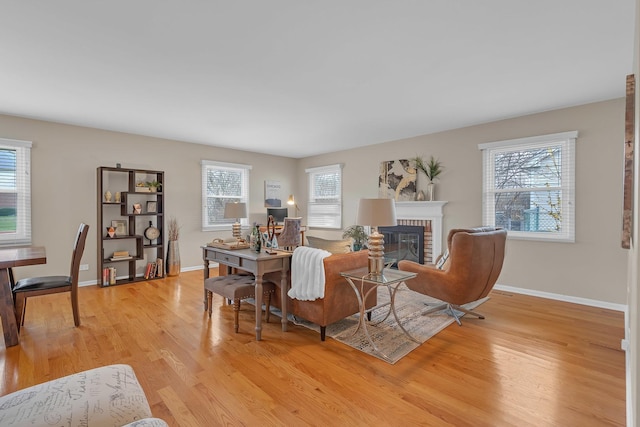 living area with light wood-type flooring, a fireplace, and baseboards