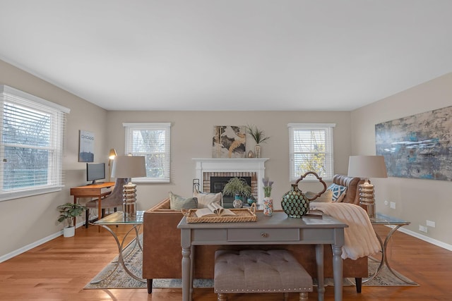 living area featuring wood finished floors, baseboards, and a brick fireplace
