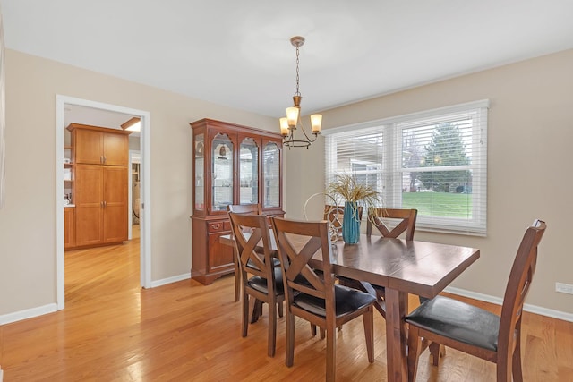 dining area featuring a chandelier, light wood-type flooring, and baseboards