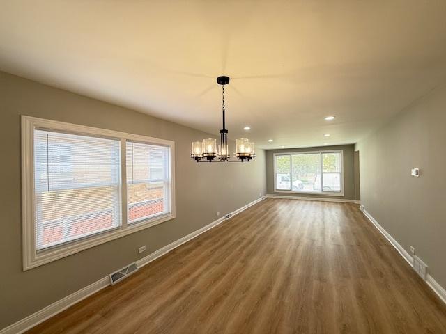 unfurnished dining area with a chandelier, wood finished floors, baseboards, and recessed lighting
