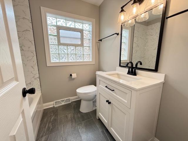 bathroom featuring toilet, vanity, and baseboards