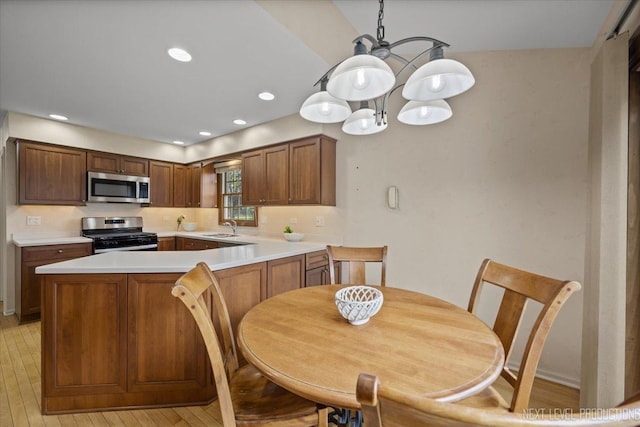 554 Carriage Hill Rd, Naperville, IL 60565 - kitchen featuring stainless steel appliances, a sink, a chandelier, light countertops, and a peninsula