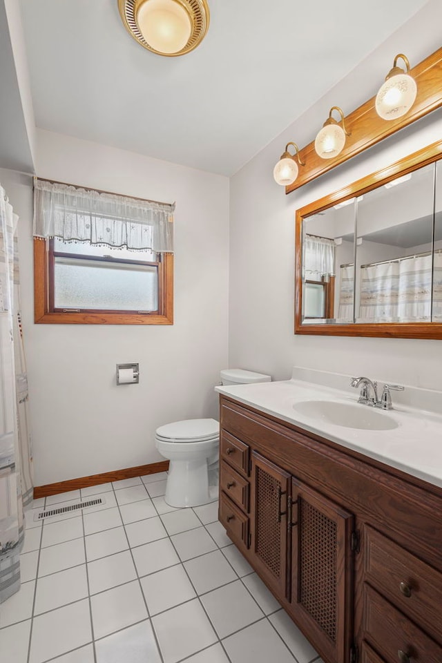 bathroom with toilet, vanity, tile patterned flooring, and baseboards