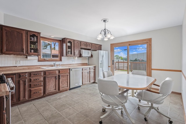 kitchen featuring appliances with stainless steel finishes, decorative backsplash, a chandelier, light countertops, and a sink