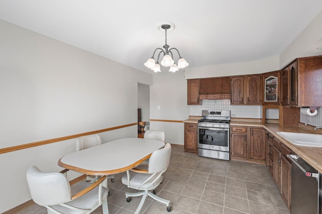 kitchen featuring appliances with stainless steel finishes, decorative backsplash, a sink, a chandelier, and light countertops