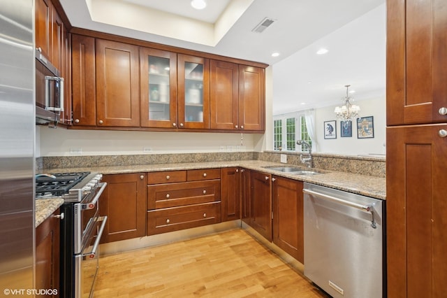 518 Winnetka Ave Unit 203, Winnetka, IL 60093 - kitchen with stainless steel appliances, a sink, light wood-style floors, a chandelier, and glass insert cabinets