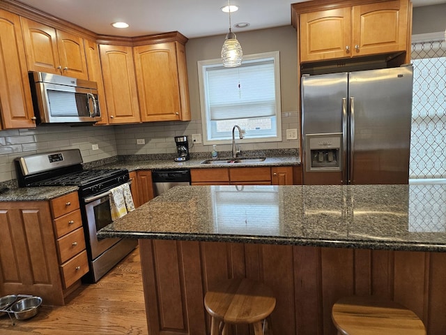 6710 W Harts Rd, Niles, IL 60714 - kitchen featuring appliances with stainless steel finishes, a sink, light wood-style flooring, a kitchen breakfast bar, and dark stone countertops