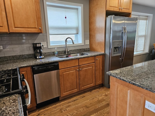 6710 W Harts Rd, Niles, IL 60714 - kitchen featuring stainless steel appliances, a sink, light wood finished floors, dark stone countertops, and decorative backsplash