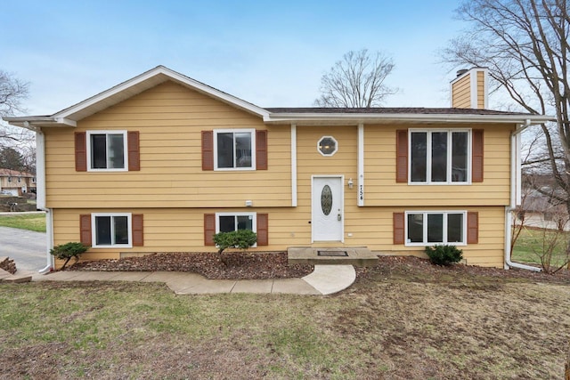 bi-level home featuring a chimney and a front yard