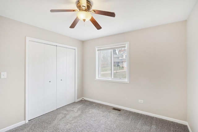 unfurnished bedroom featuring light colored carpet, a closet, baseboards, and ceiling fan