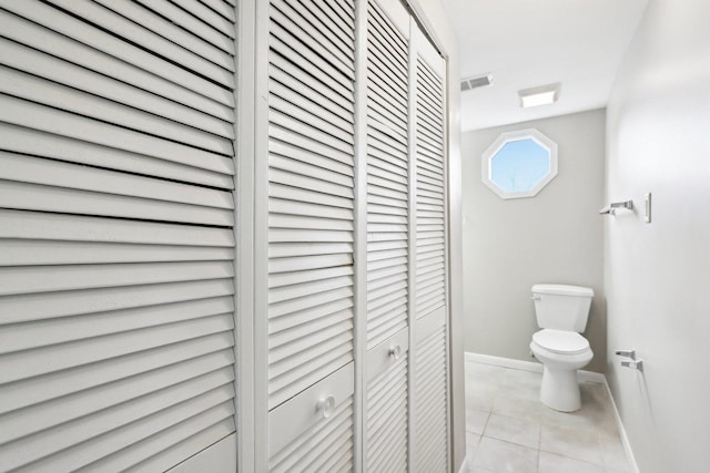 bathroom with a closet, toilet, tile patterned flooring, and baseboards