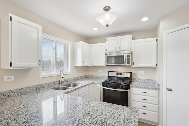 kitchen with stainless steel appliances, a sink, light stone countertops, white cabinetry, and recessed lighting