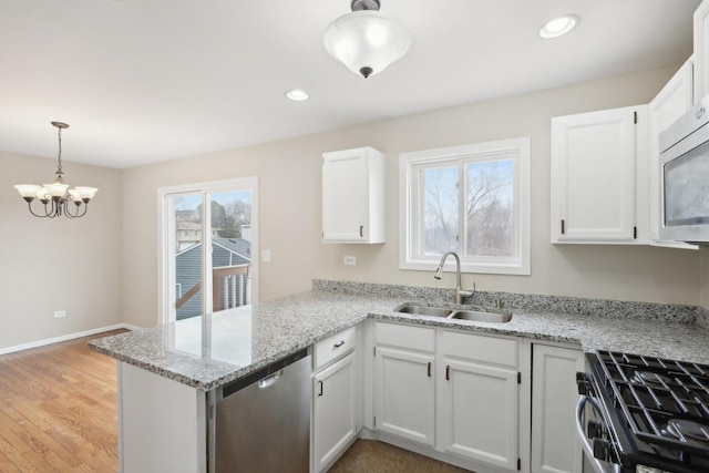 kitchen with a sink, stainless steel appliances, a peninsula, a chandelier, and white cabinets