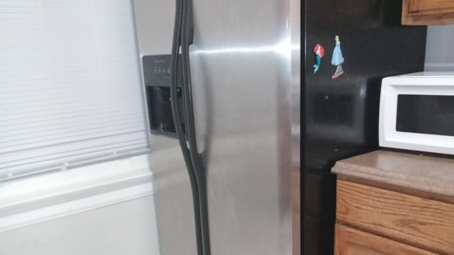 7421 S Eberhart Ave, Chicago, IL 60619 - kitchen view of stainless steel refrigerator with ice dispenser, white microwave, and brown cabinets