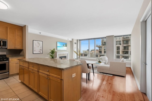 33 W Ontario St Unit 25H, Chicago, IL 60654 - kitchen with appliances with stainless steel finishes, open floor plan, a fireplace, a center island, and stone countertops