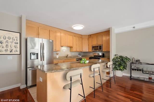 33 W Ontario St Unit 25H, Chicago, IL 60654 - kitchen featuring stainless steel appliances, light brown cabinetry, a kitchen island, baseboards, and a kitchen breakfast bar