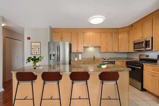 33 W Ontario St Unit 25H, Chicago, IL 60654 - kitchen with stainless steel appliances, a sink, light brown cabinets, and a breakfast bar area