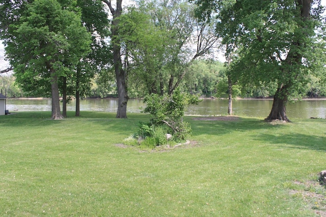 view of green lawn featuring a water view