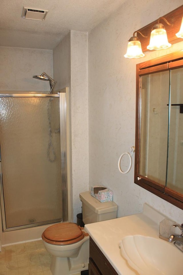 bathroom with a shower stall, vanity, toilet, and a textured ceiling