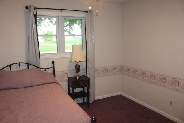 bedroom featuring dark carpet and baseboards