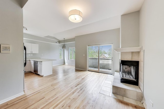 2136 W Evergreen Ave Unit 3B, Chicago, IL 60622 - unfurnished living room featuring lofted ceiling, light wood-style floors, a tiled fireplace, and baseboards