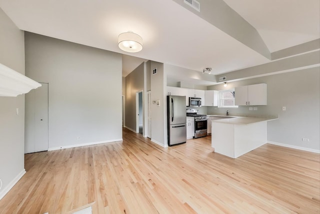 2136 W Evergreen Ave Unit 3B, Chicago, IL 60622 - kitchen with appliances with stainless steel finishes, a peninsula, light countertops, white cabinets, and light wood-style floors