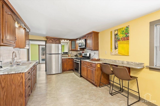 206 Walnut St, Cherry Valley, IL 61016 - kitchen with stainless steel appliances, a sink, brown cabinetry, tasteful backsplash, and light floors