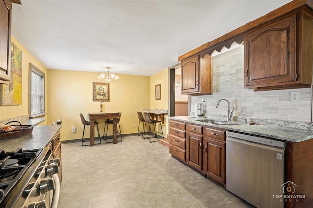 206 Walnut St, Cherry Valley, IL 61016 - kitchen featuring appliances with stainless steel finishes, a sink, decorative backsplash, a chandelier, and baseboards