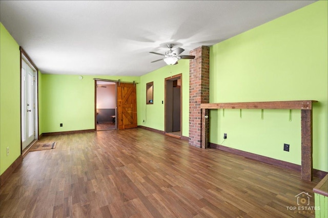 206 Walnut St, Cherry Valley, IL 61016 - unfurnished living room with a barn door, wood finished floors, a ceiling fan, and baseboards