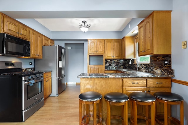 17708 Walter St, Lansing, IL 60438 - kitchen featuring appliances with stainless steel finishes, a peninsula, a sink, light wood-type flooring, and brown cabinetry
