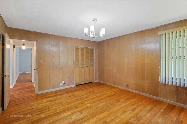 5049 Birchwood Ave, Skokie, IL 60077 - unfurnished room with a chandelier, light wood-style flooring, wood walls, and baseboards