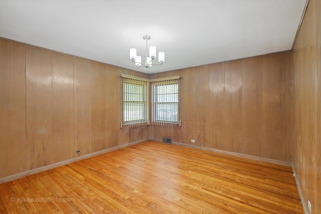 5049 Birchwood Ave, Skokie, IL 60077 - spare room featuring a chandelier, wood finished floors, wooden walls, and baseboards