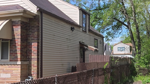 view of side of property featuring fence and brick siding