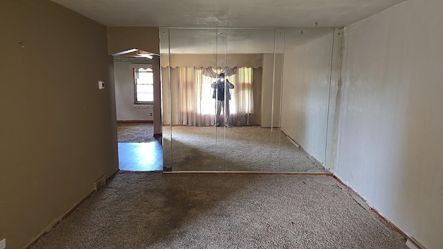 empty room featuring carpet flooring and a baseboard heating unit