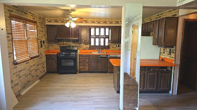 kitchen with gas stove, ceiling fan, light wood-type flooring, backsplash, and brick wall