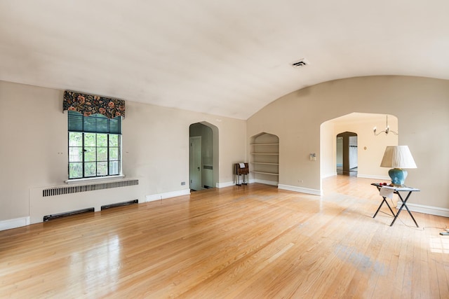 1753 N Normandy Ave, Chicago, IL 60707 - unfurnished living room featuring radiator heating unit, arched walkways, wood-type flooring, baseboards, and lofted ceiling