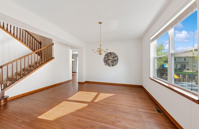 2739 Moraine Valley Rd, Wauconda, IL 60084 - empty room with stairs, a chandelier, light wood finished floors, and baseboards