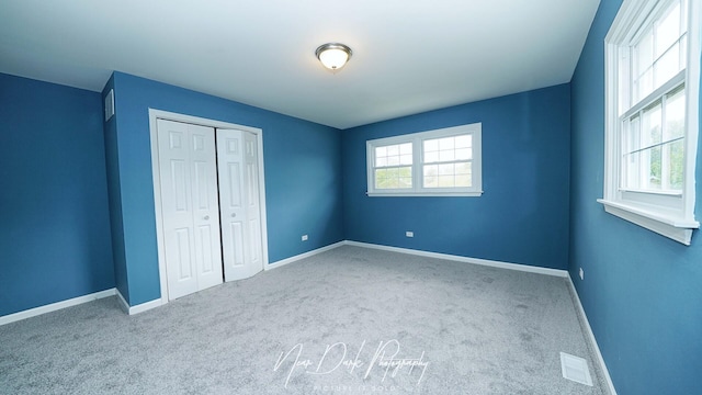 unfurnished bedroom with carpet, a closet, and baseboards