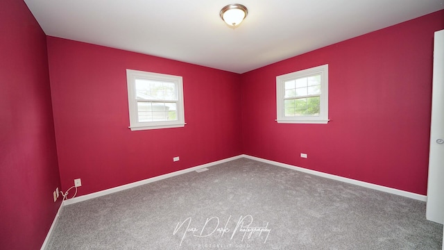 carpeted spare room featuring healthy amount of natural light and baseboards
