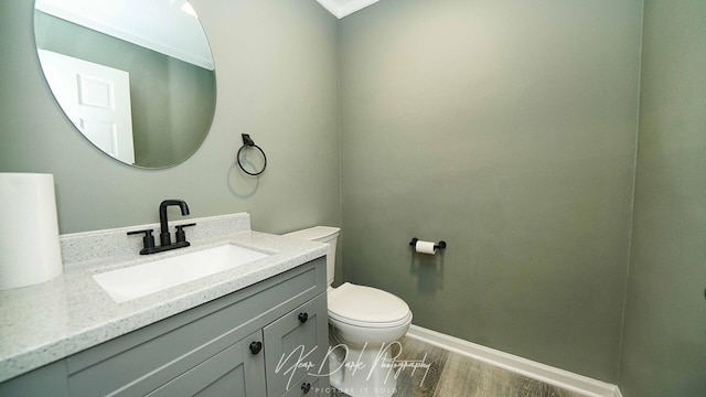bathroom featuring vanity, toilet, wood finished floors, and baseboards