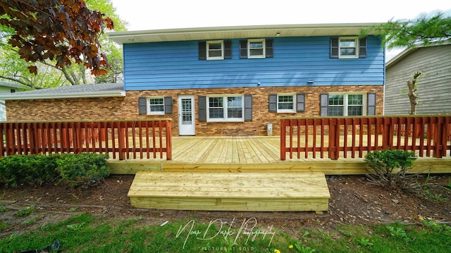 back of property with brick siding and a wooden deck