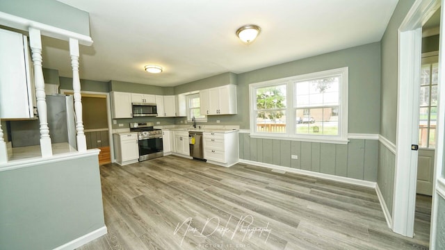 kitchen featuring stainless steel appliances, a sink, light countertops, light wood finished floors, and white cabinets