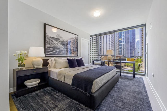 bedroom featuring baseboards, a wall of windows, and a city view