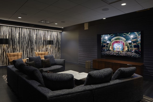 cinema featuring a paneled ceiling, baseboards, wood finished floors, and an accent wall