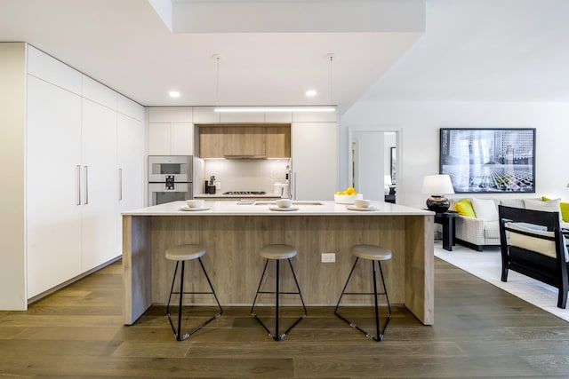 kitchen featuring modern cabinets, a sink, a kitchen bar, and recessed lighting