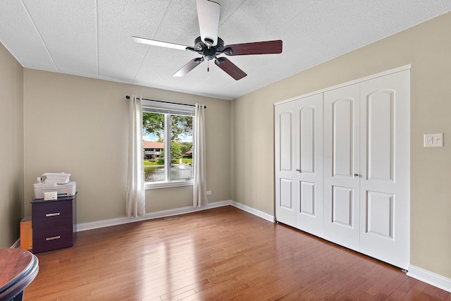 13151 S Westview Dr Unit 1B, Palos Heights, IL 60463 - unfurnished bedroom with wood finished floors, a closet, a textured ceiling, a ceiling fan, and baseboards