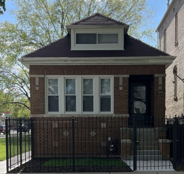 bungalow with brick siding, a fenced front yard, and a gate