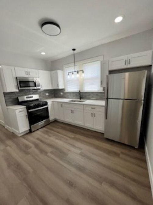 kitchen featuring appliances with stainless steel finishes, a sink, white cabinetry, tasteful backsplash, and recessed lighting