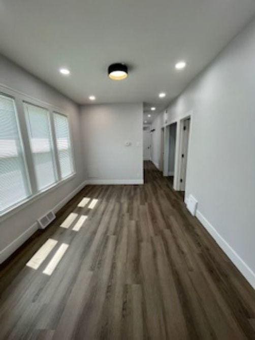unfurnished living room with baseboards, dark wood-style flooring, and recessed lighting