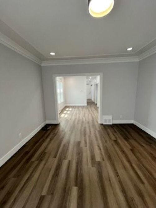 empty room featuring baseboards, ornamental molding, wood finished floors, and recessed lighting